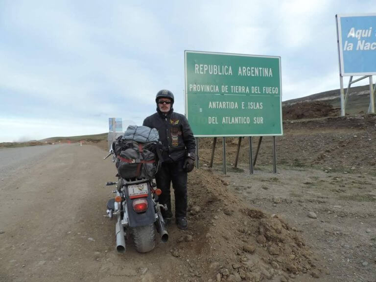 Peace and brotherhood advocate Mario Nieves poses in front of a travel sign in Argentina during his travels to promote peace among nations. Photo courtesy of Mario Nieves