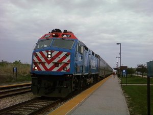 Metra 207 pulls in lightly smoking and hauling 6 cars into Mokena – Hickory Creek station. (Photo credit: Wikipedia)