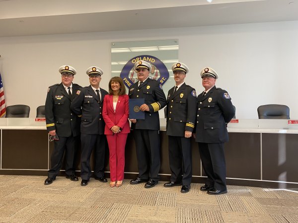 Congresswoman Marie Newman present the Orland Fire Protection District with a copy of a state of praise to be entered into the Congressional Record in September. Newman (center) poses with OFPD Chief Michael Schofield (3rd from left) and the OFPD Battalion Chiefs. Photo courtesy of the Orland Fire Protection District.