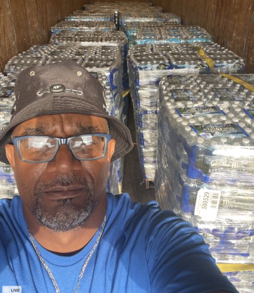 State Rep. Cyril Nicholas, with the thousands of bottles of water collected to fill two 18-wheel semi-trucks to help the water-starved residents of Jackson, Mississippi on Saturday Sept. 3