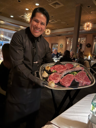 Sullivan's Steakhouse server Jairo with plate of steak options